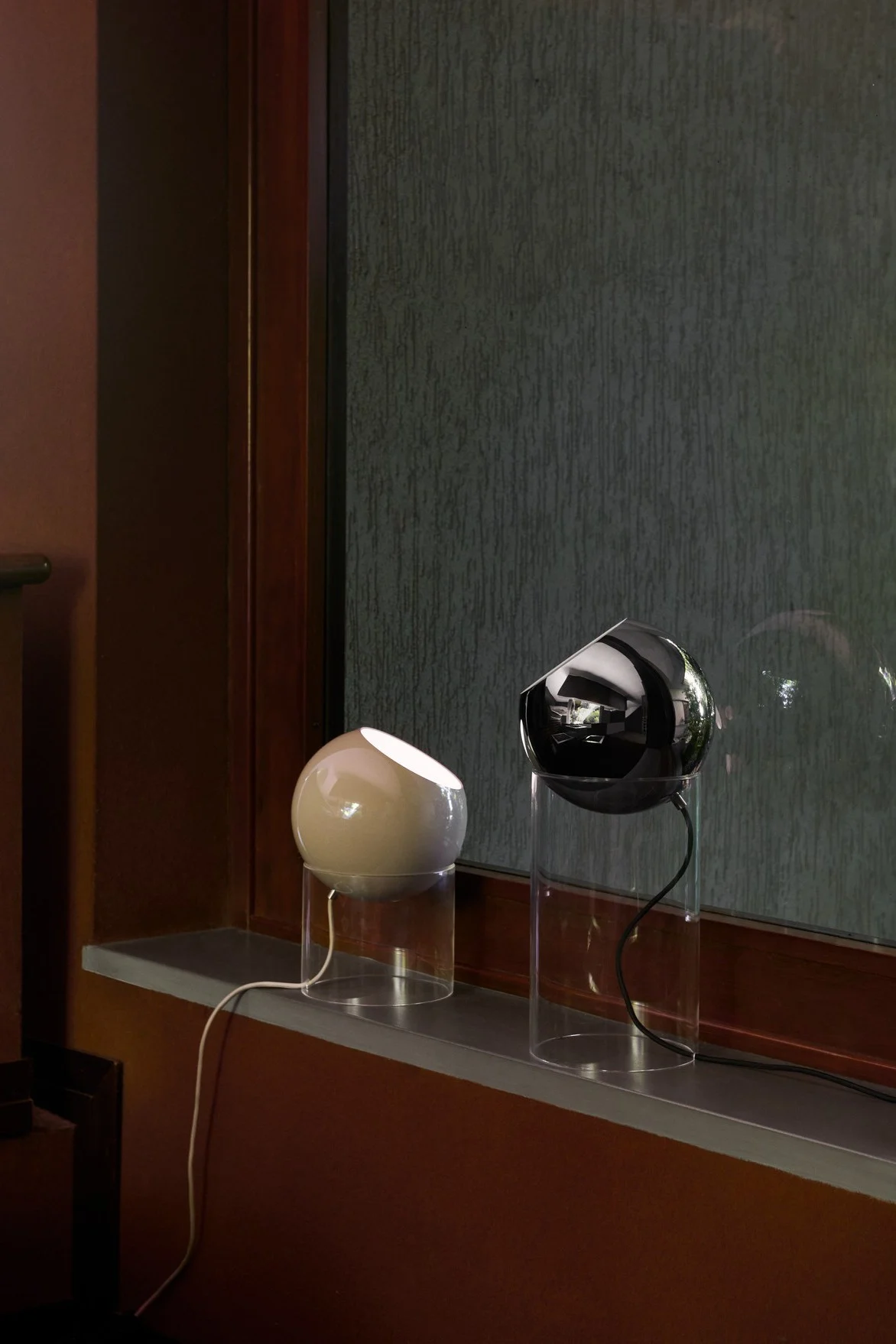 Ikkunalaudalla on kaksi eri kokoista &Traditionin Topan pöytävalaisinta beigenä ja mustana.