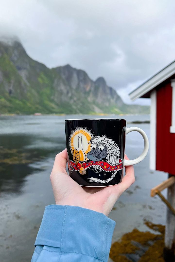 @moominbyingri pitää kädessään Urahn-muumikuppia, taustalla karu norjalainen maisema.