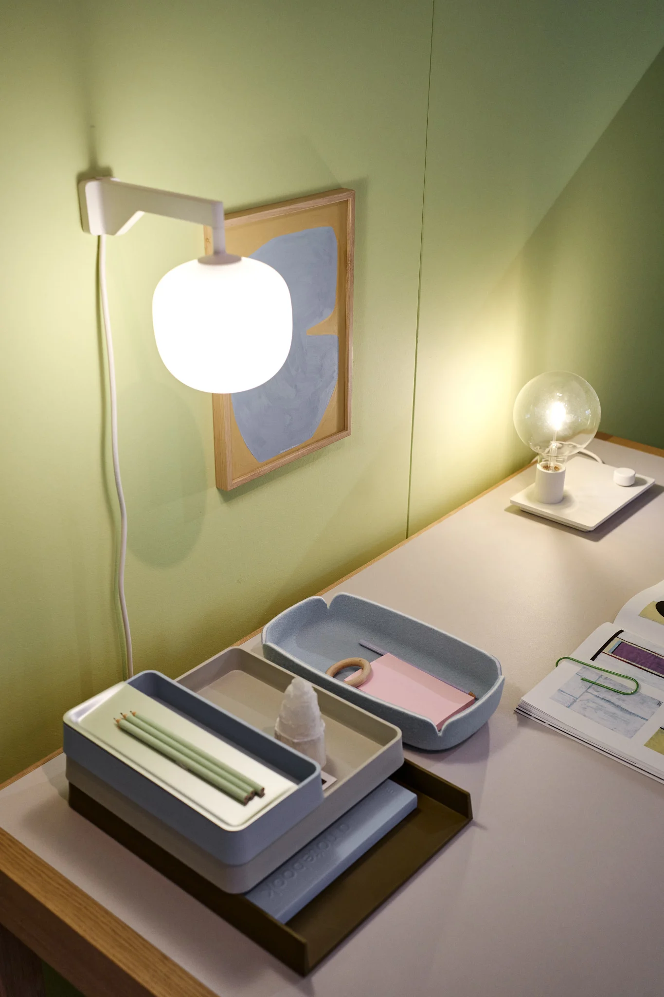 Siisti työpöytä vihreän seinän edessä Muuton beigenvärisellä Rime-seinävalaisimella.