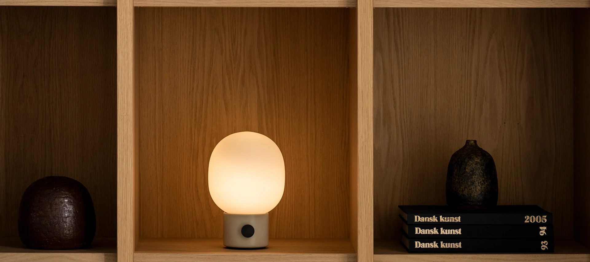 Hyllyllä on Audo Copenhagenin valaiseva JWDA-pöytävalaisin.