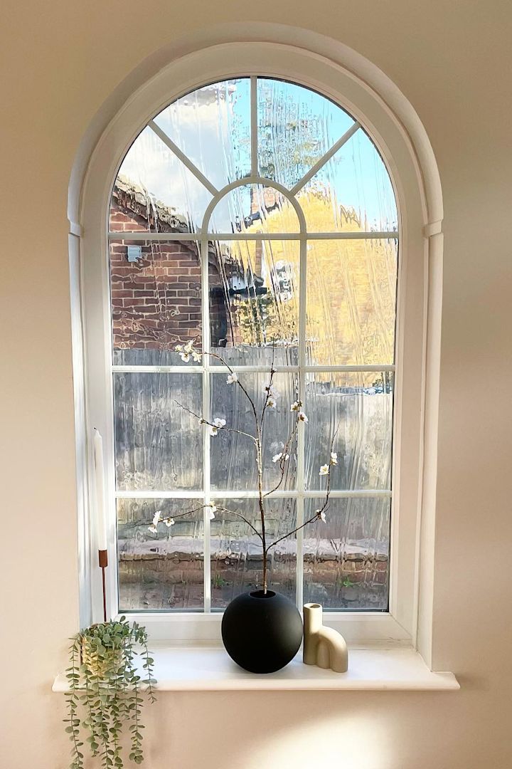 Tässä näet @abrysonhouse:n tekemän kauniin kaari-ikkunan ikkunalaudalla, joka on koristeltu kynttilänjaloilla ja Cooee Designin mustalla pallomaljakolla, jossa on kevätkukkia.