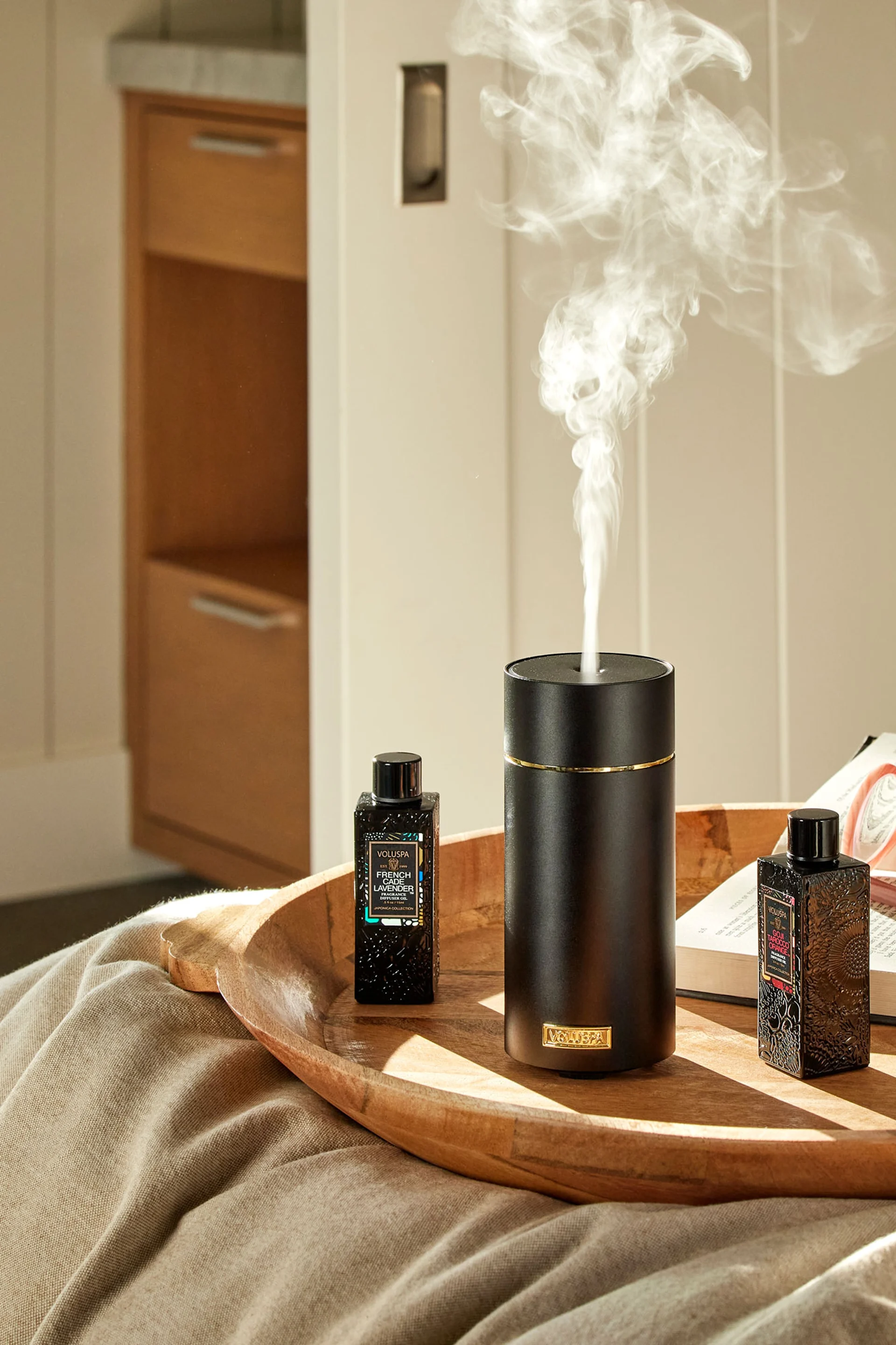 Volantin harmaa kividiffuusori seisoo kirjapinon päällä peilin edessä, ja sen vieressä on kasvi. Anna se lahjaksi äitienpäiväksi luomaan kylpylätunnelmaa.