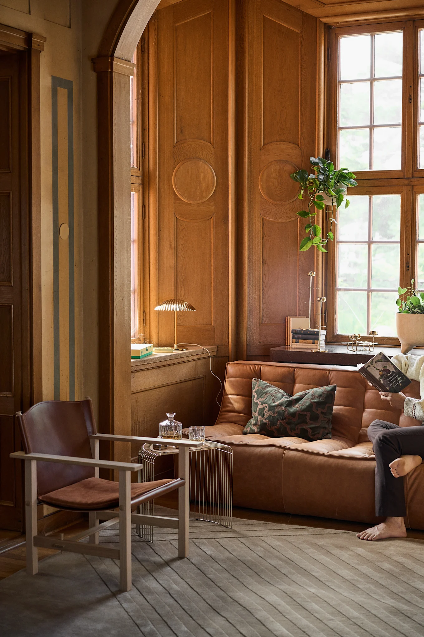 Huone, jossa on puupanelointi ja ruskea nahkasohva ja nojatuoli, heijastavat 1960-luvun tyyliä ja vuoden 2026 sisustustrendejä.