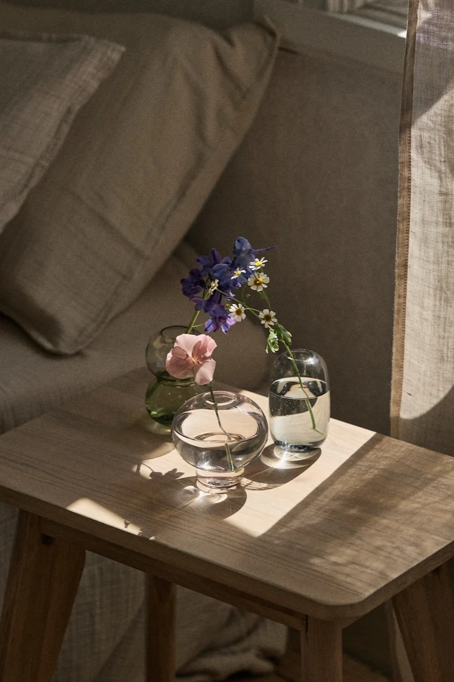 Ikkunalaudalla on useita pieniä maljakoita yksittäisille kukille tai pienille kukkakimpuille. 