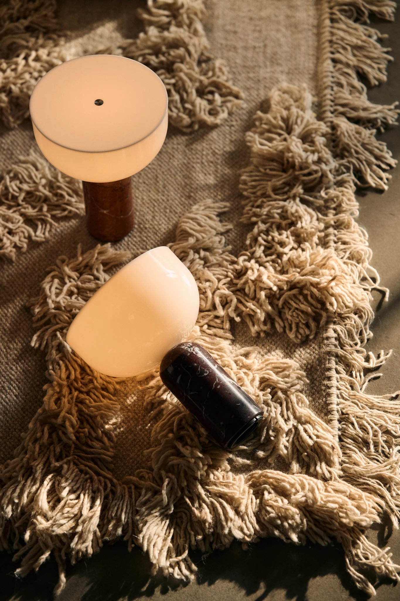 Mattoon on asetettu kaksi skandinaavista lamppua – New Worksin Kizu-pöytävalaisimet.