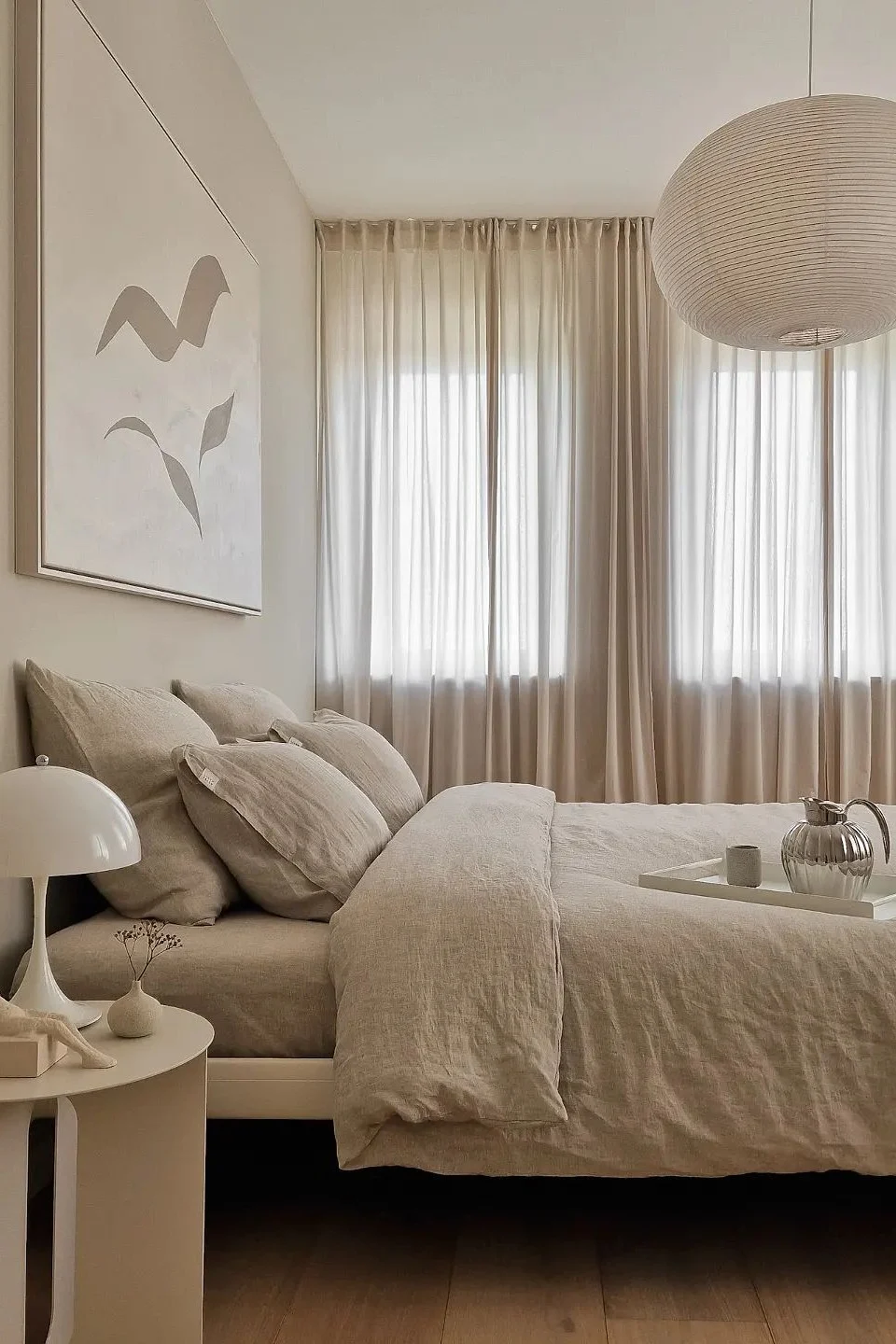 @homagine:n viihtyisä, feng shui -periaatteiden mukaisesti sisustettu beige makuuhuone, jossa on Bernadotte-kannu ja Panthella-pöytävalaisin.