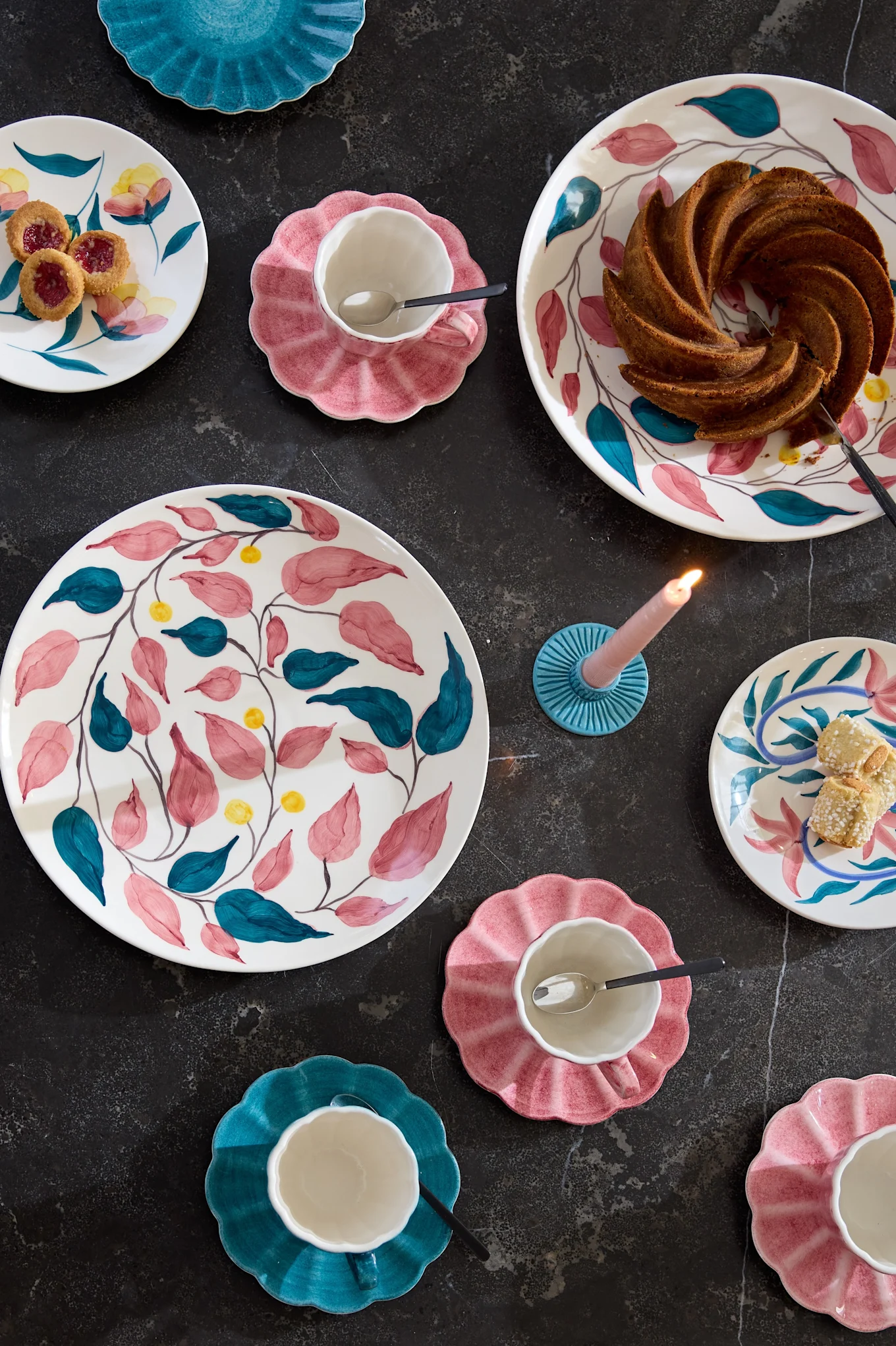 Pöytäkaluste, jossa on Mateuksen Flowers-malliston värikkäitä astioita.