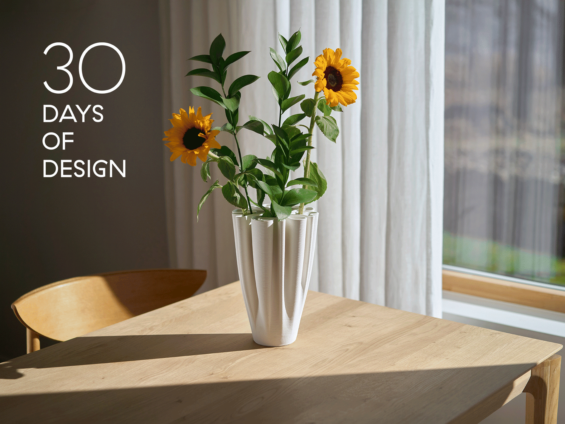 Valkoinen laskostettu maljakko auringonkukilla puupöydällä. Tekstissä lukee '30 DAYS OF DESIGN'.