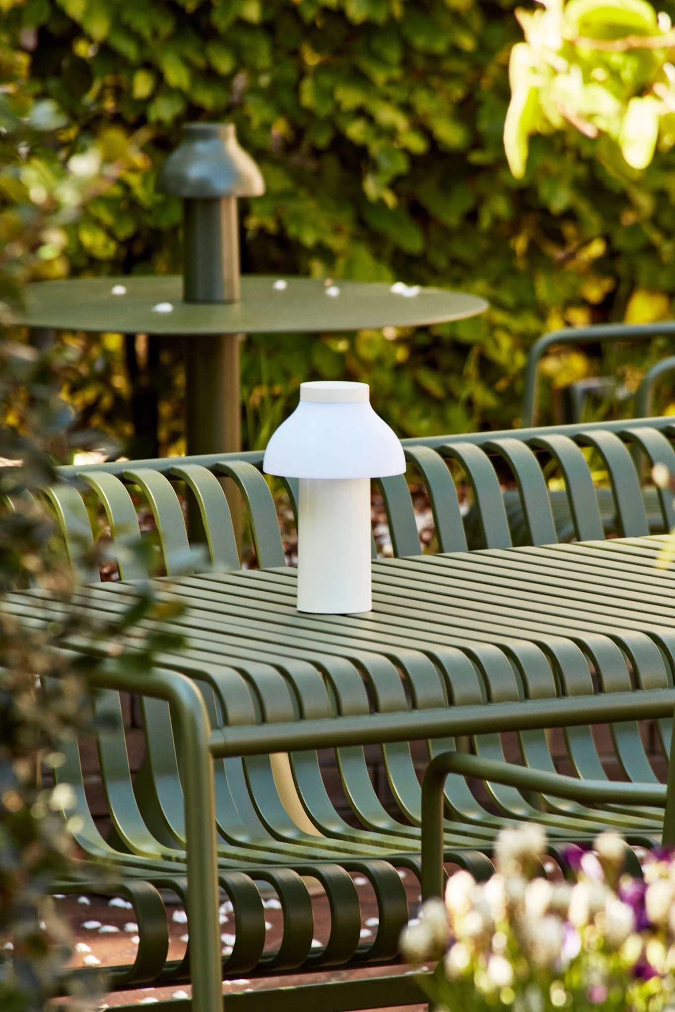 PC portable valkoinen ladattava pöytävalaisin, joka seisoo ulkona vihreällä pöydällä. 