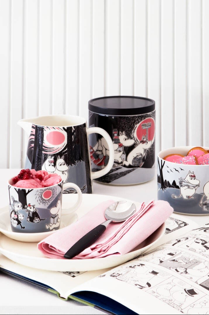 Moomin Adventure -kokoelma, joka koostuu kupista, lautasesta, kannusta, tölkistä ja kulhosta, seisoo pöydällä.