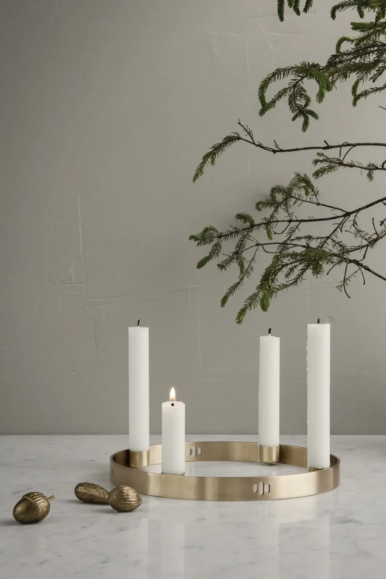 Ferm Livingin Circle Messing -kynttilänjalka seisoo pöydällä yksinkertaisessa ympäristössä.