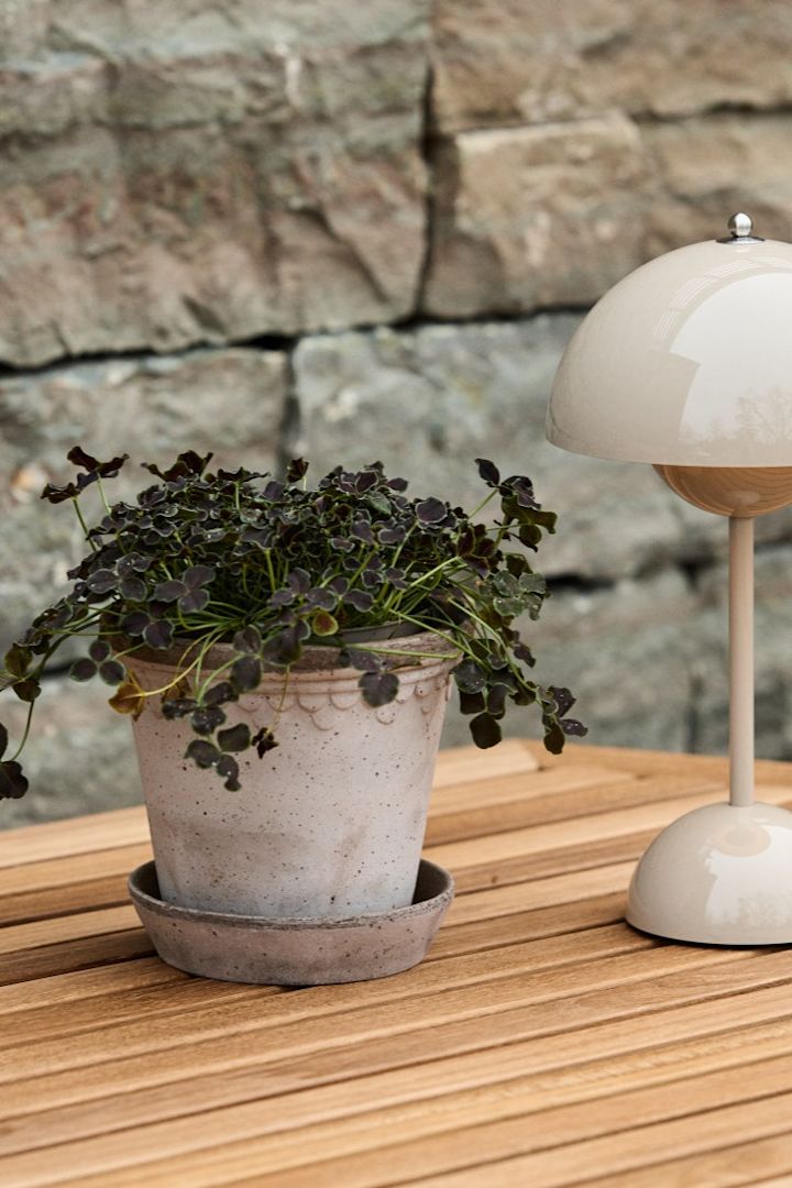 Copenhangen kukkaruukku seisoo puisella ruokapöydällä kannettavan Flowerpot VP9 -pöytävalaisimen kanssa.
