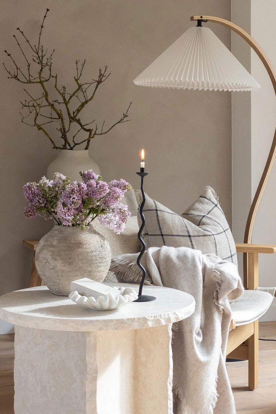 Marmorinen sohvapöytä, joka on koristeltu kukilla, kulholla ja kynttilänjalalla, kaikki rustiikkisessa tyylissä.