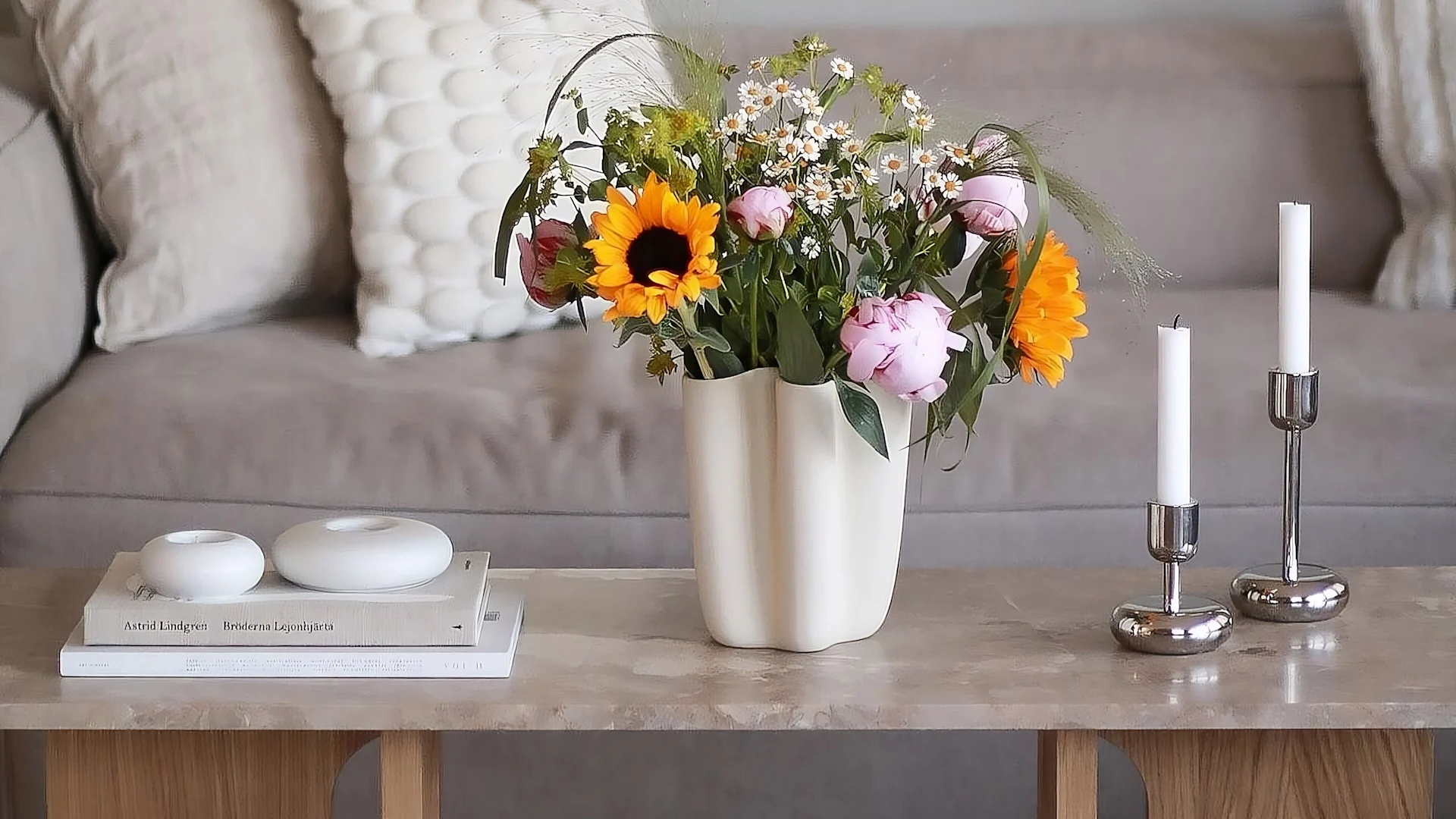 Audo Copenhagenin androgyyninen sohvapöytä on koristeltu tuoreilla kukilla, kahdella Iittalan Nappula-kynttilänjalalla ja Scandi Livingin Stone-kynttilänjaloilla.