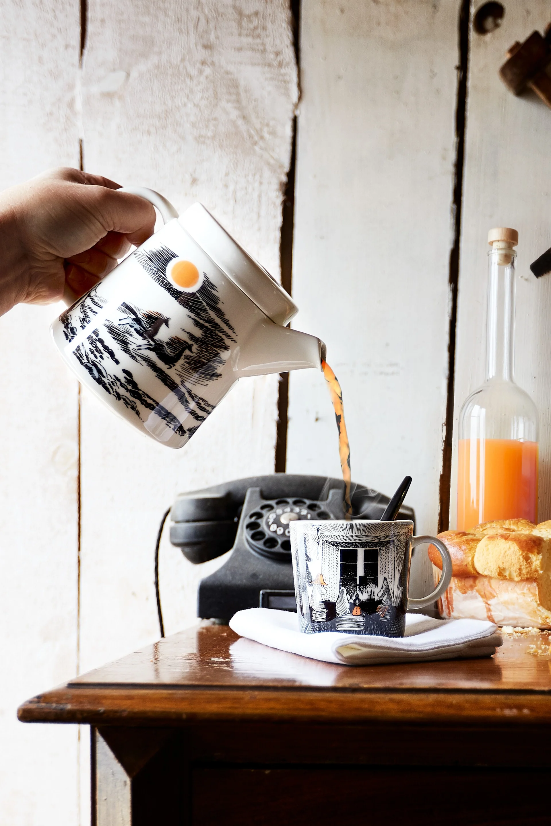 Alkuperäistä tyyliä: Joku kaataa teetä Muumi-kannusta vastaavaan Muumi-kuppiin.