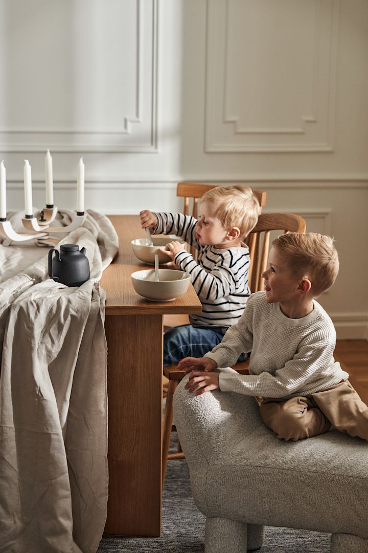 Kaksi poikaa istuu Design House Stockholm merkin ruokapöydän ääressä, ja kuvassa näkyy myös Lulu rahi ja kulhot NM&Sand-sarjasta.