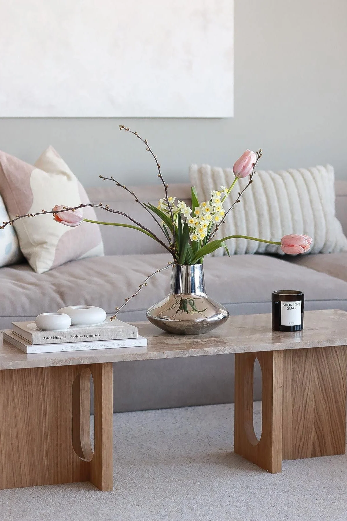 @picsbyellenin keväisesti koristeltu sohvapöytä: Audo Copenhagenin Androgyne-loungepöydällä on Georg Jensenin kromivärinen Henning Koppel -maljakko, jossa on tulppaaneja, ja sen vieressä kynttilöitä ja kynttilänjalkoja.