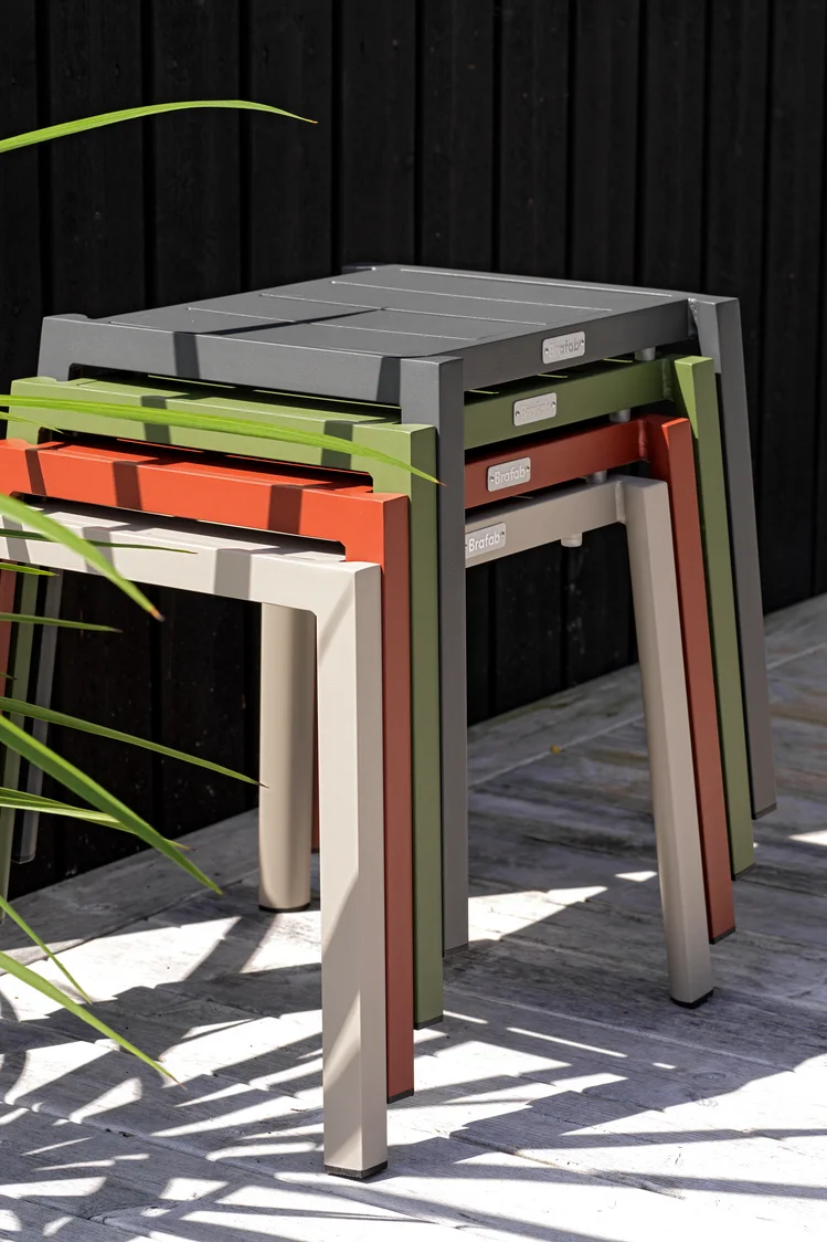 Puutarhakalustetrendeihin 2025 kuuluvat myös monikäyttöiset kalusteet. Brafabin Delia-malliston jakkarat, tässä neljässä eri värissä päällekkäin pinottuina, ovat tilaa säästäviä ja monipuolisesti käytettäviä.