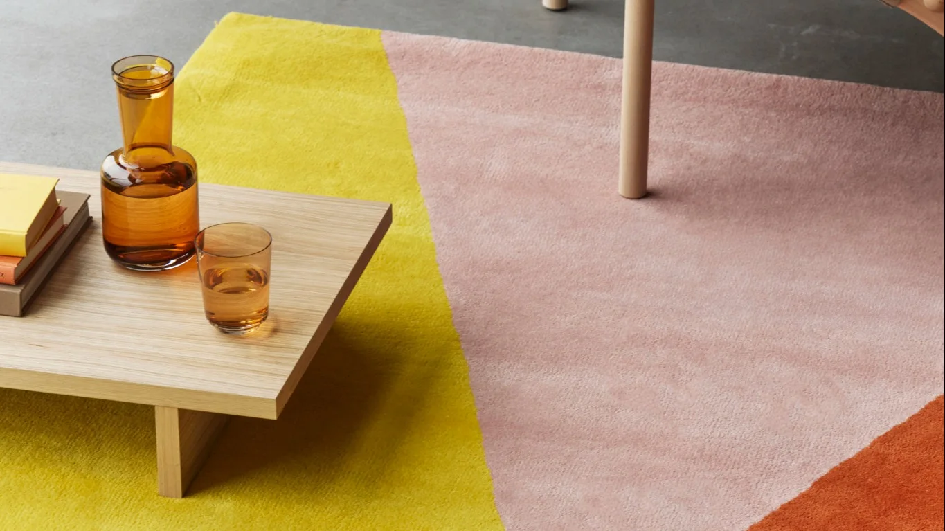 Olohuone, jossa on beige matto ja vihreitä villapeittoja NJRD Edges -mallistosta.