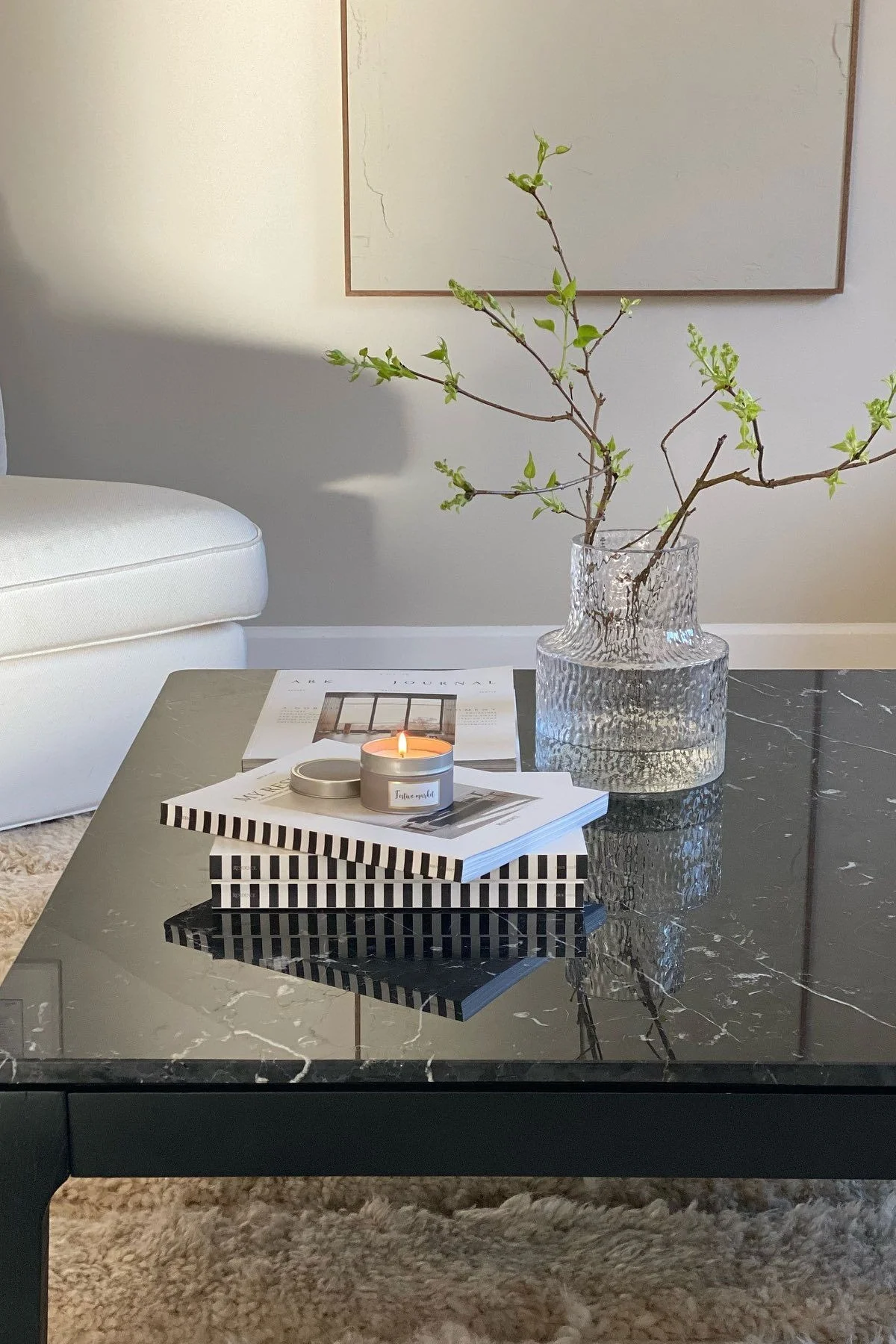 Musta sohvapöytä, koristeltu kirjoilla ja Skrufs Kolonn -maljakolla.