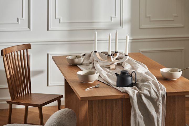 Tyylikäs ruokailutila, jossa on merkin Design Housen Stockholm puinen pöytä, Family-tuoli, pellavakangas ja mustaa posliinia kulhojen ja teekannun muodossa.