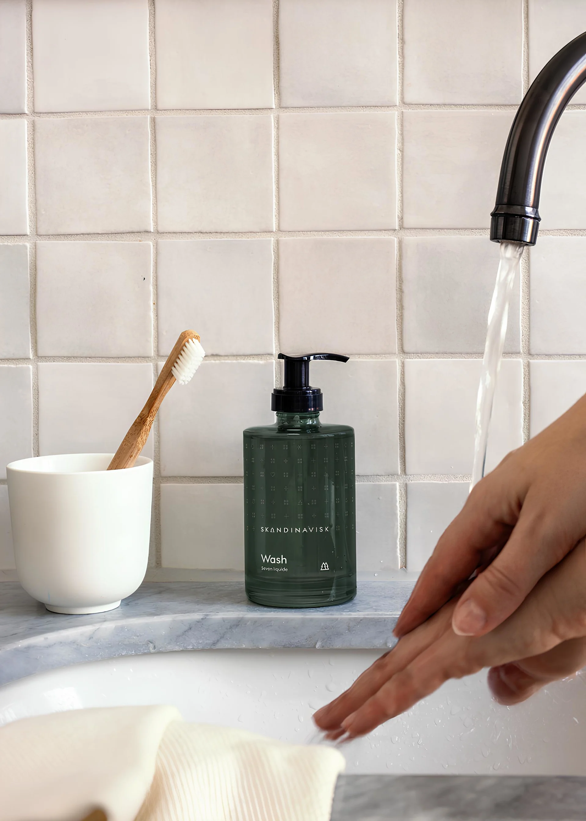 Ystävänpäivälahja: Lahjoita spa-hetkiä. Kuvassa Skandinaviskin Skog-saippua on pesualtaan päällä, kun henkilö pesee käsiään.