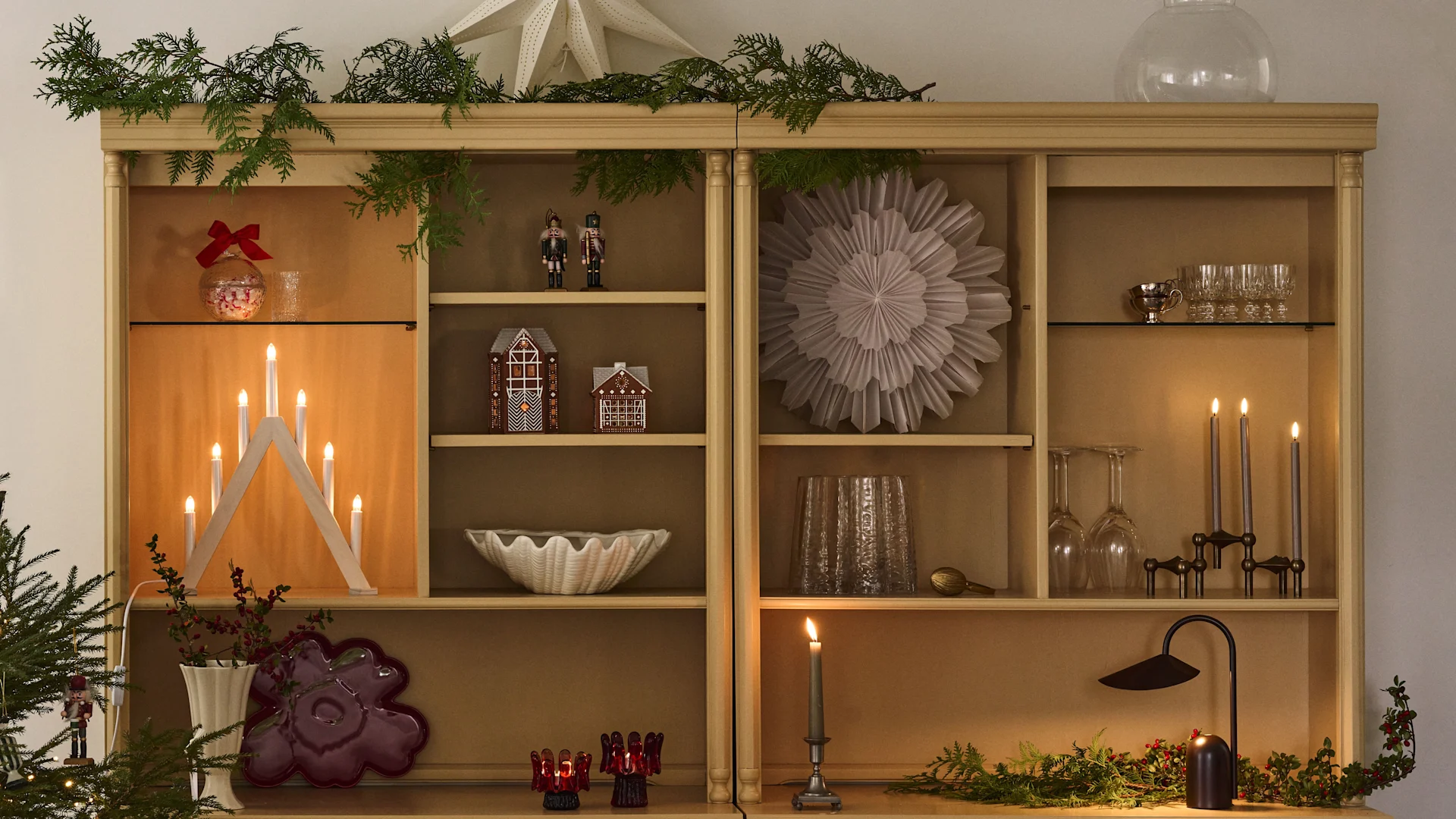 Joulukoristeltu kirjahylly, jossa on joulutähtiä ja kynttilänjalka, sopii täydellisesti ensimmäisen adventin tunnelmaan. 