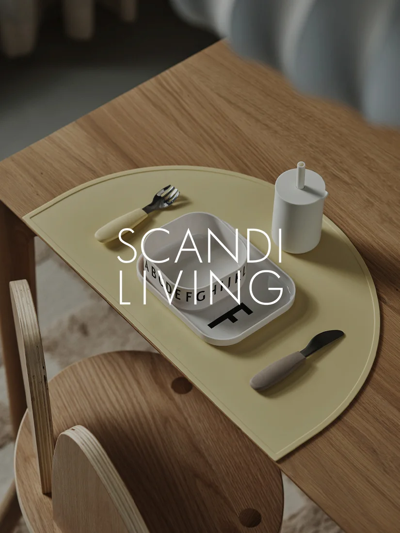 Puinen lastenpöytä, jossa keltainen kattausalusta, valkoinen lautane aakkosin, kuppi, haarukka ja veitsi.