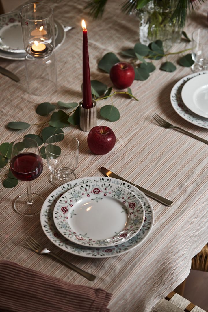 Yksinkertainen joulupöydän kattausidea Swedish Grace Winterillä, punaisilla kynttilöillä ja viherkasveilla. 