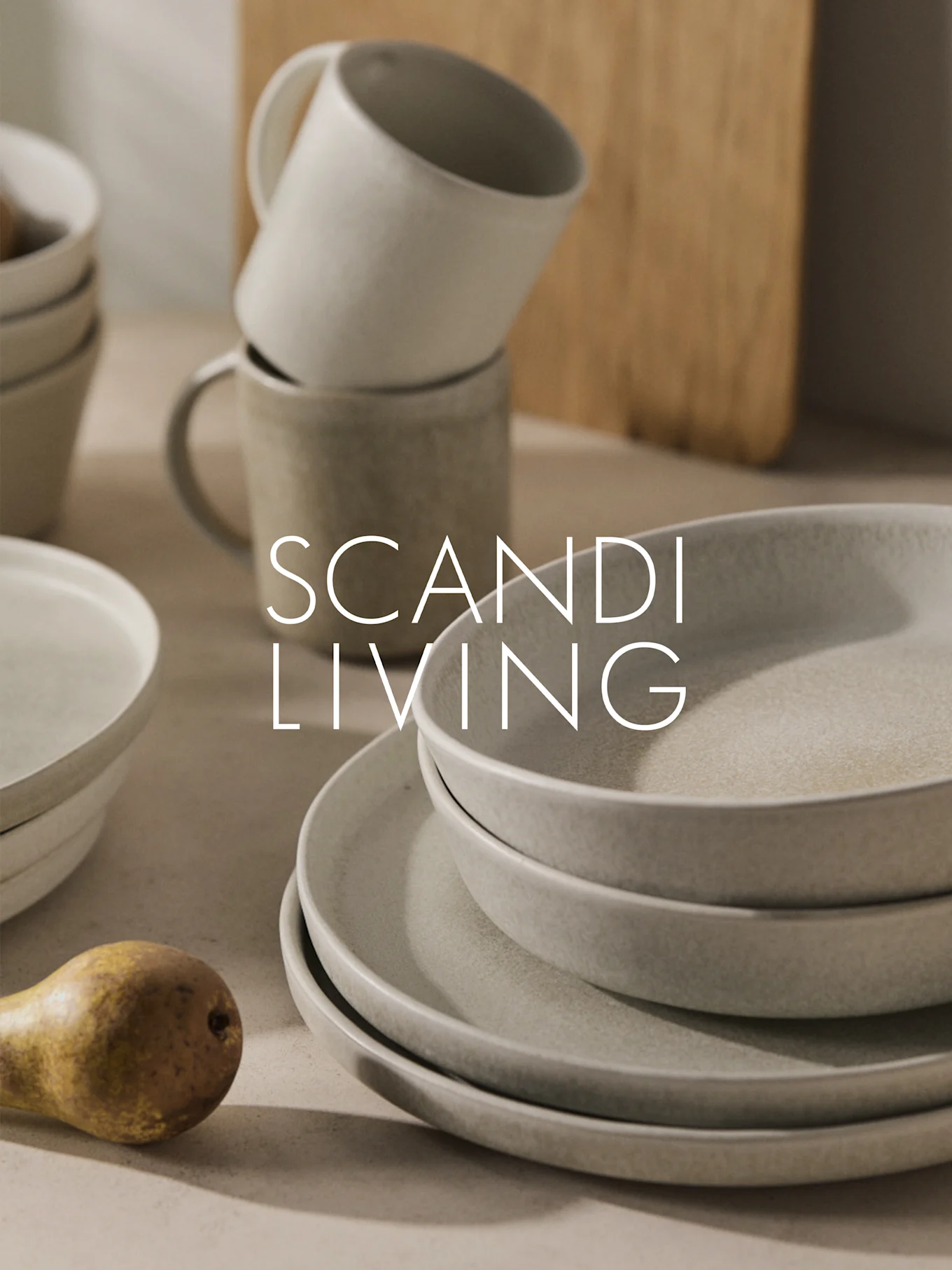 Pinottuja beigejä keraamisia astioita, mukeja ja päärynä sekä "SCANDI LIVING" -teksti.
