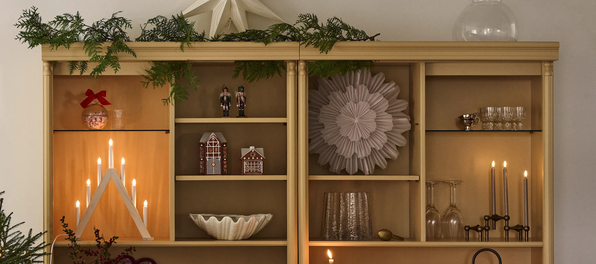 Joulukoristeltu kirjahylly, jossa on joulutähtiä ja kynttilänjalka, sopii täydellisesti ensimmäisen adventin tunnelmaan. 