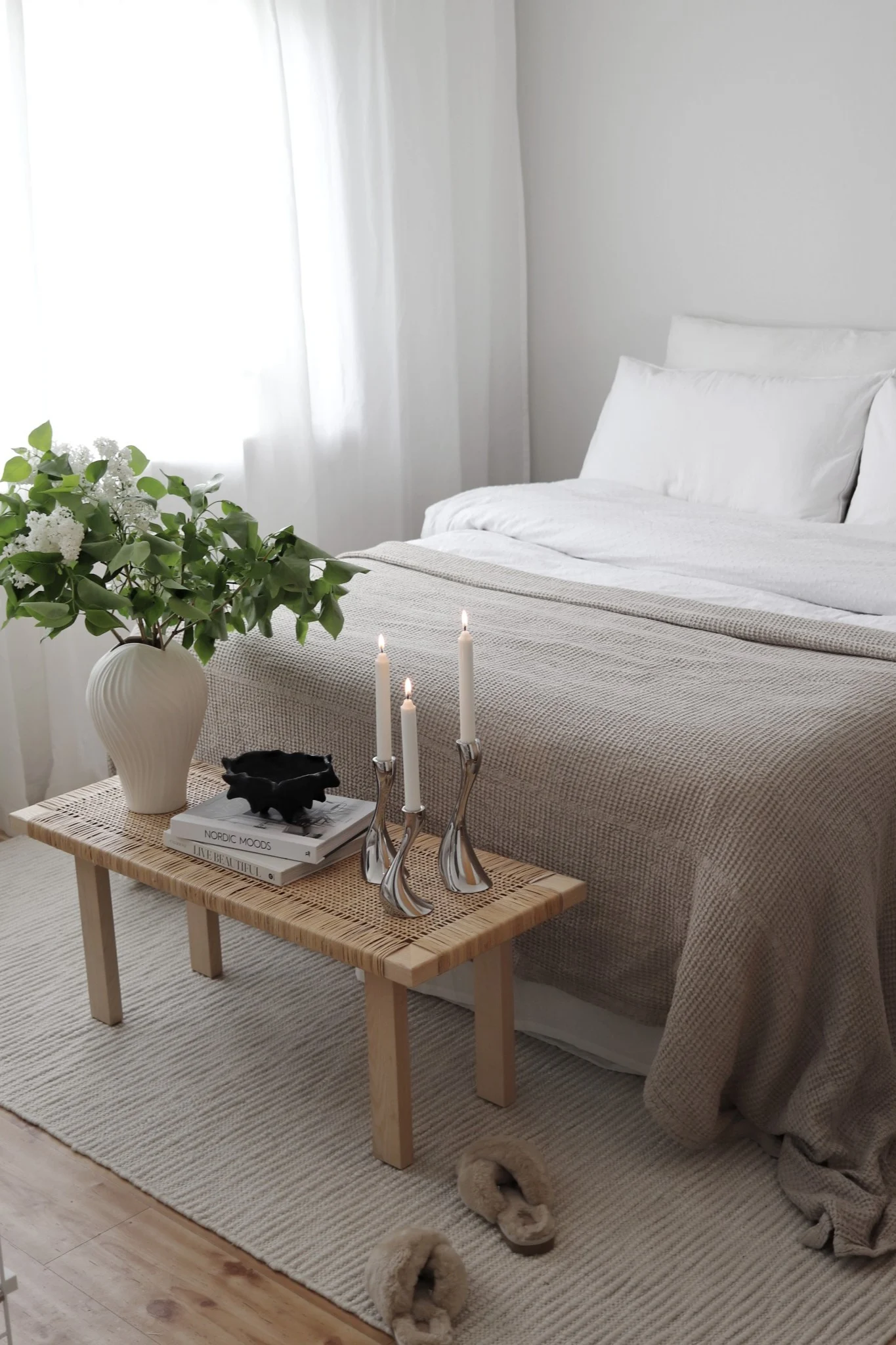 Makuuhuoneen matot: Scandi Livingin valkoinen Pebble-villamatto on puoliksi sängyn alla, ja sängyn juurella on pieni penkki, joka on koristeltu kasvilla ja kynttilöillä. @hemmahosfalk
