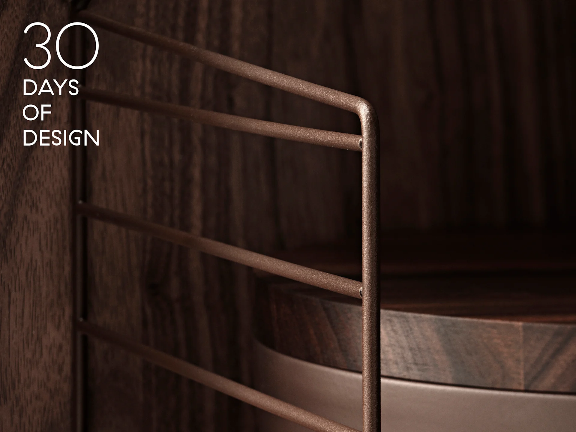 Teksti '30 DAYS OF DESIGN' tumman puukaapin päällä, jossa kuvioitu ruskea metalliverkkoteline ja pyöreä puuhylly.