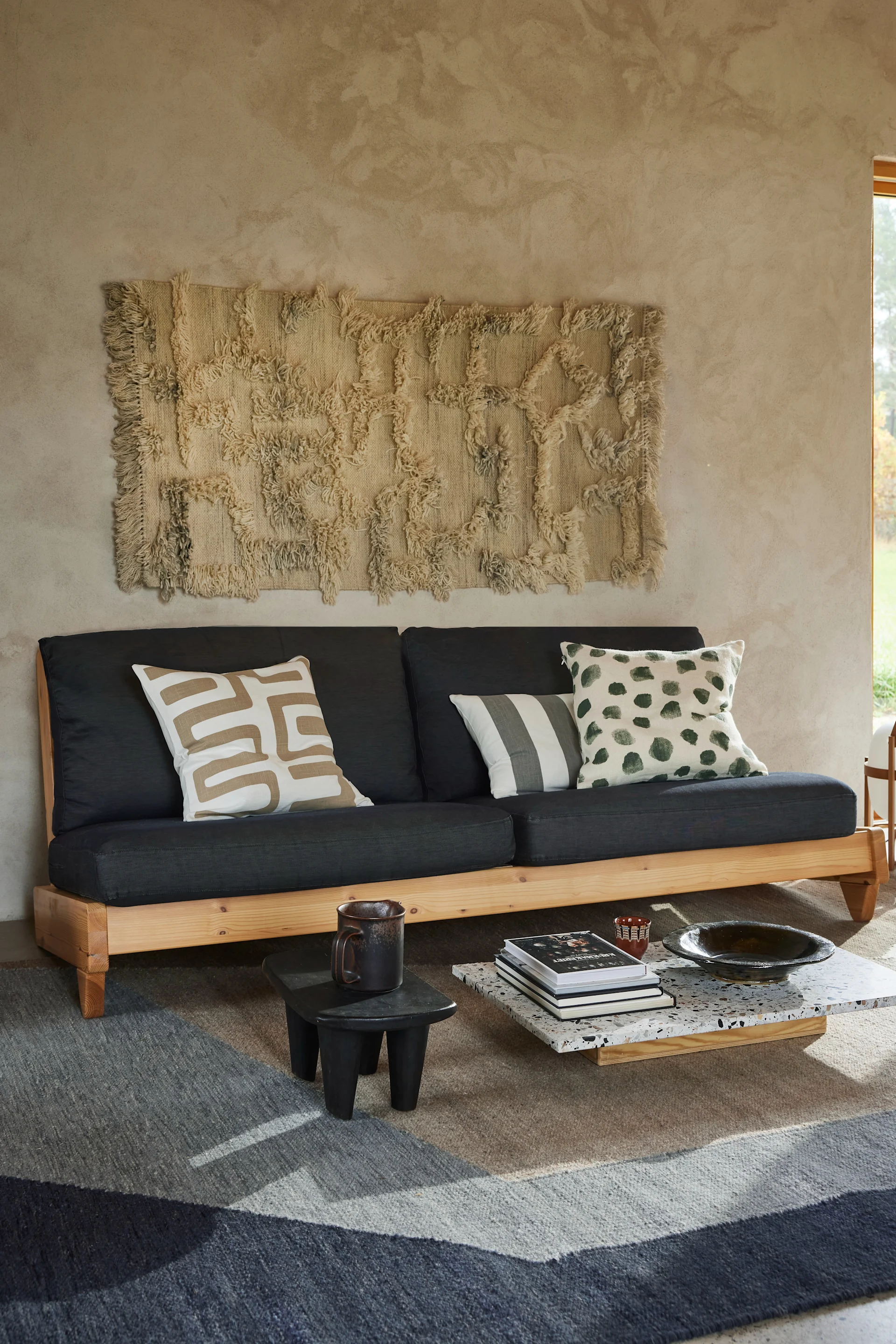 Koristele seinä Classic Collectionin Rio-matolla. Matto roikkuu olohuoneessa sohvan yläpuolella.