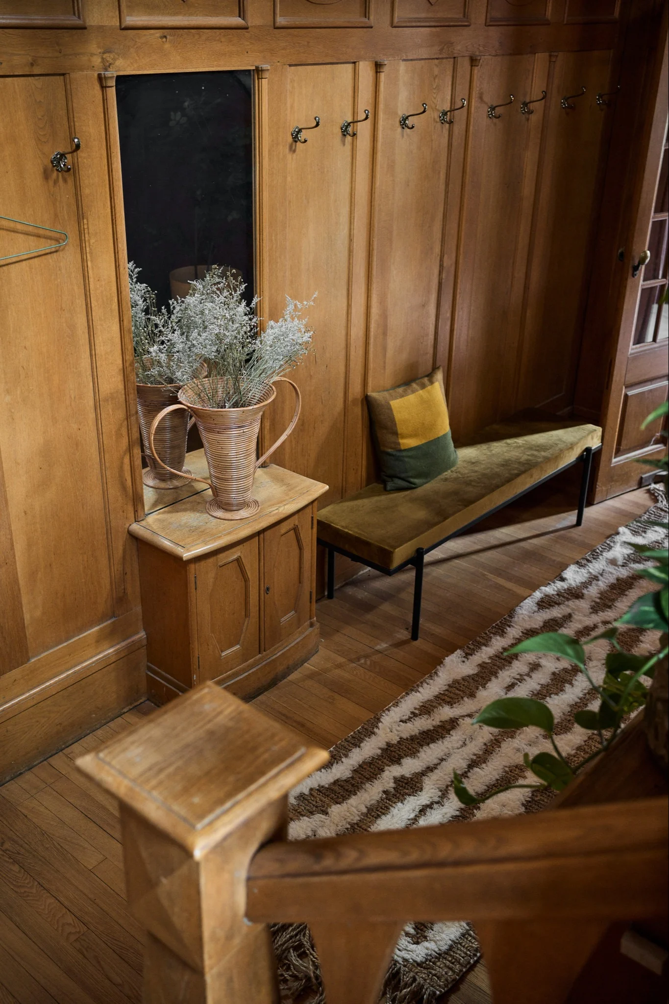 Puinen portaikko, jonka vieressä on penkki ja kuviollinen matto, luo nostalgisen kodin tunnelman ja heijastaa vuoden 2026 sisustustrendejä.