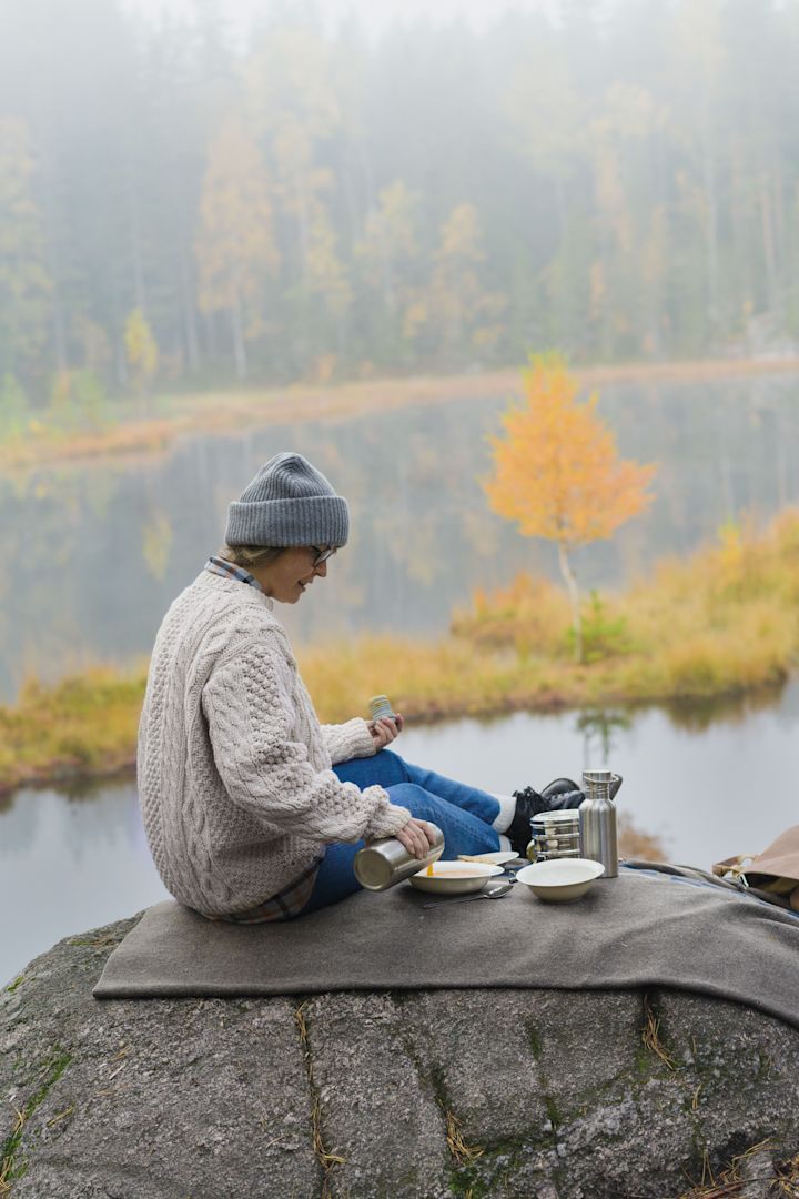 Lagom: Nainen järjestää piknikin vuorella, ympärillä on syksyinen maisema.