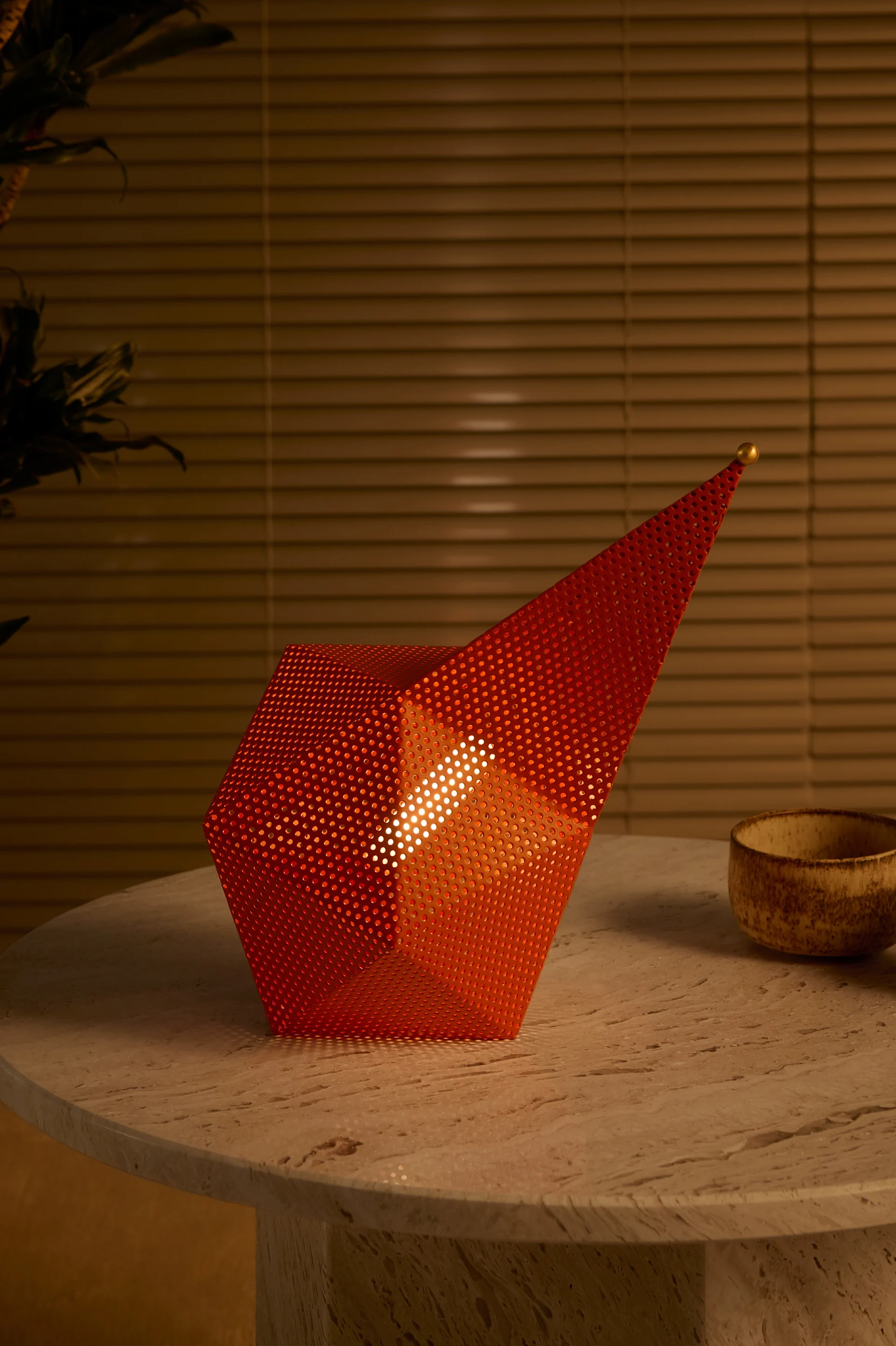 60- ja 70-luvut heräävät henkiin syksyn 2025 sisustustrendeissä: tässä Gubin oranssi kannettava pöytävalaisin seisoo puupöydällä.