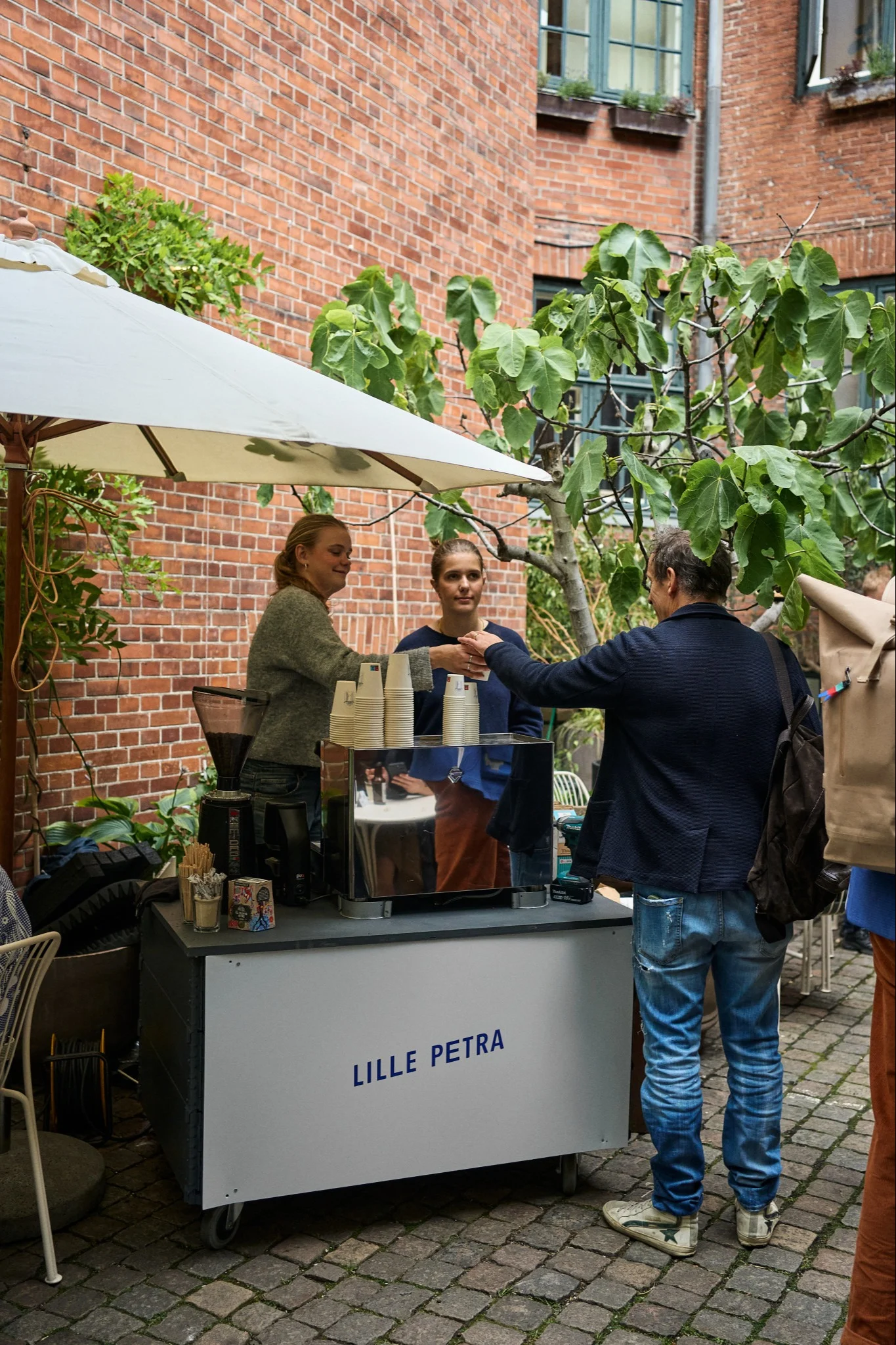 Pysähdy Lille Petra Cafessa designin ystäville suunnatulla Kööpenhaminan kaupunkikierroksella. Tässä näet henkilökunnan jakamassa kahvia sisäpihalla. 