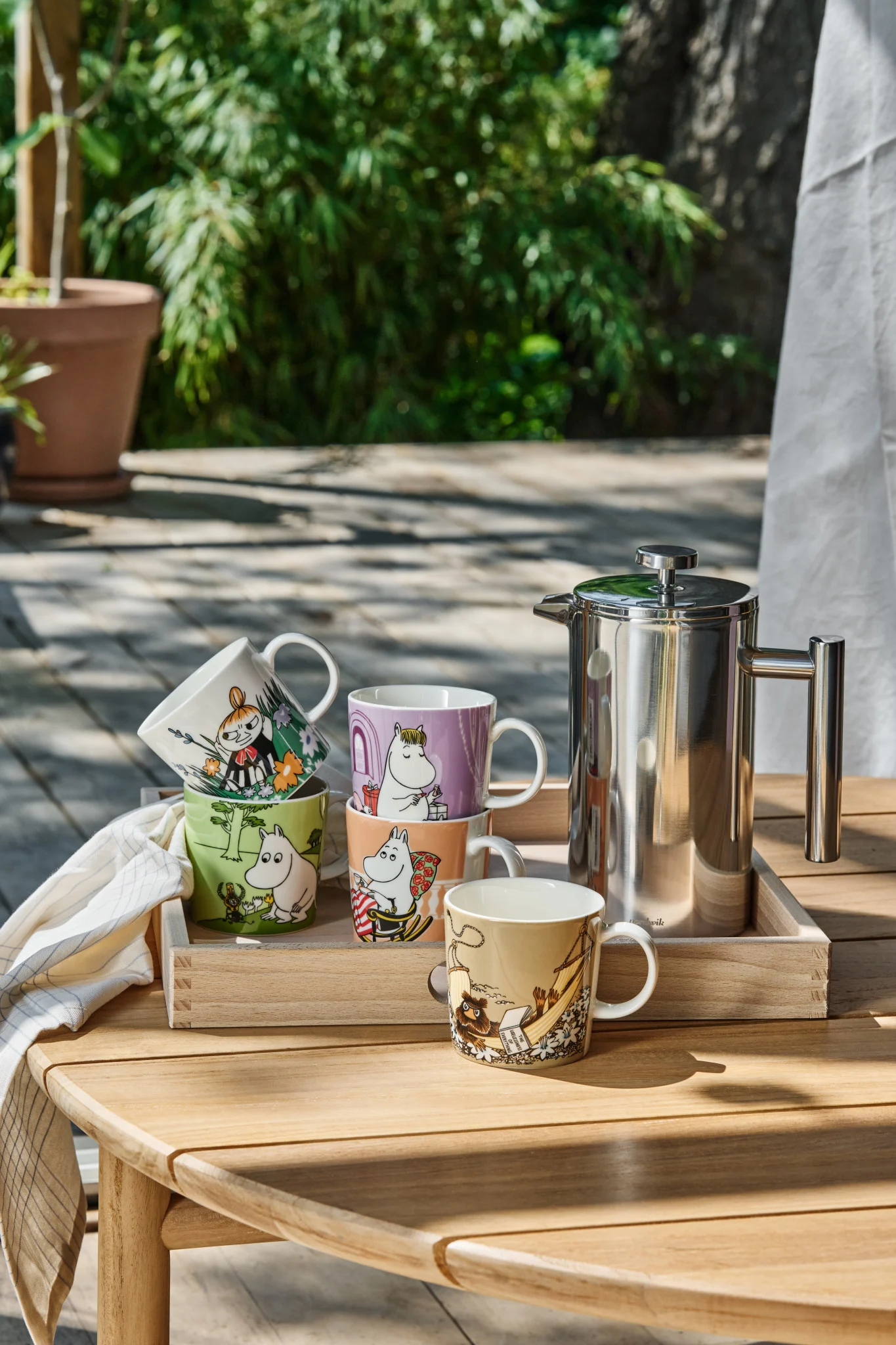 Puutarhan pöydällä on useita Muumi-kuppeja.