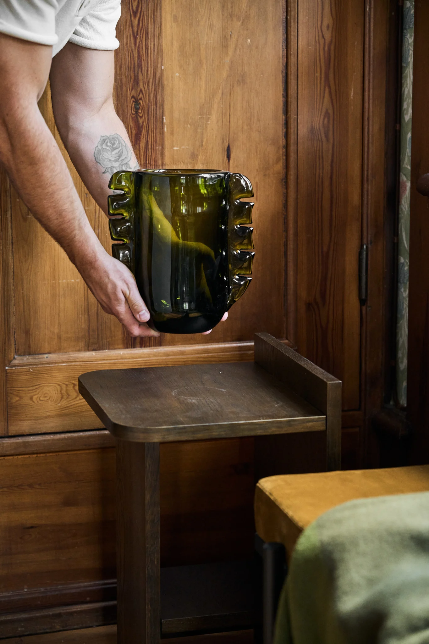 Oliivinvihreä on yksi vuoden 2026 sisustustrendeistä. Tässä kuvassa on maljakko, joka on asetettu sivupöydälle.