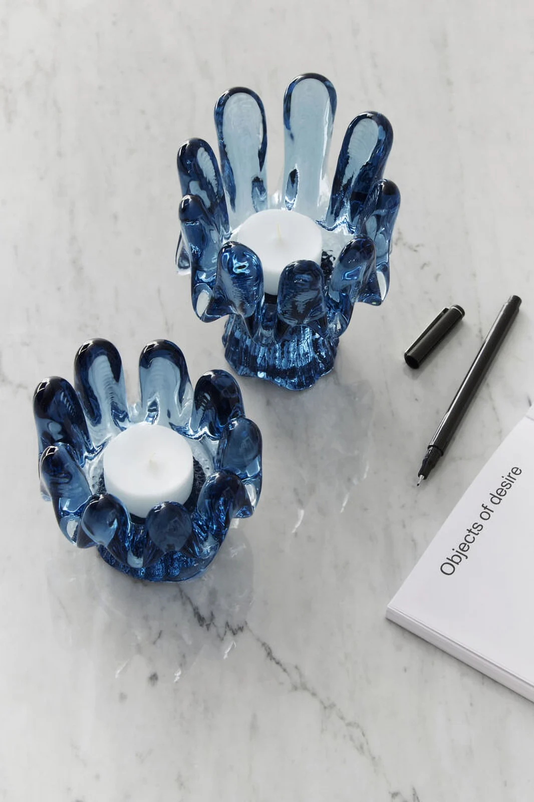 Sisustustrendit 2025: Kaksi sinistä kynttilänjalkaa Kosta Bodan Solros-kokoelmasta seisoo vaalealla pöydällä.