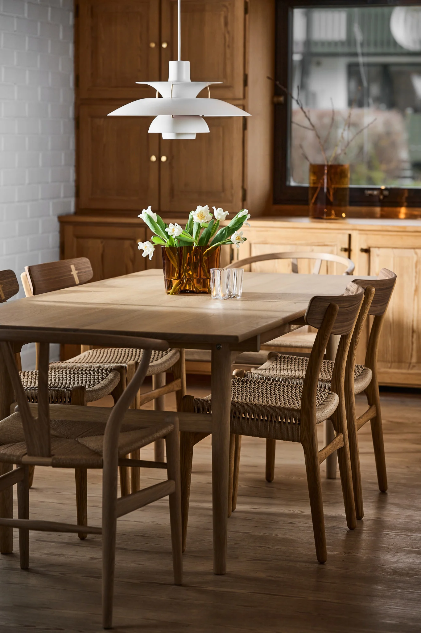 Skandinaaviset valaisimet: Louis Poulsenin valkoinen PH 5 -riippuvalaisin roikkuu ruokapöydän yläpuolella skandinaavisessa ruokasalissa.