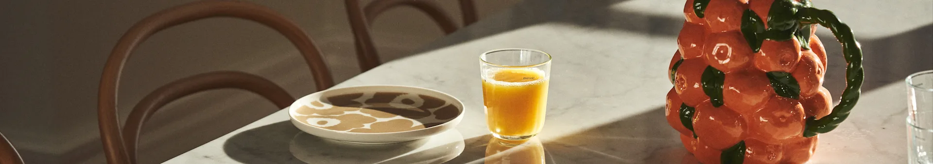 Kattaus, jossa Marimekko-posliinia, mehua ja karahvi BYON:ilta mandariinikuviolla.