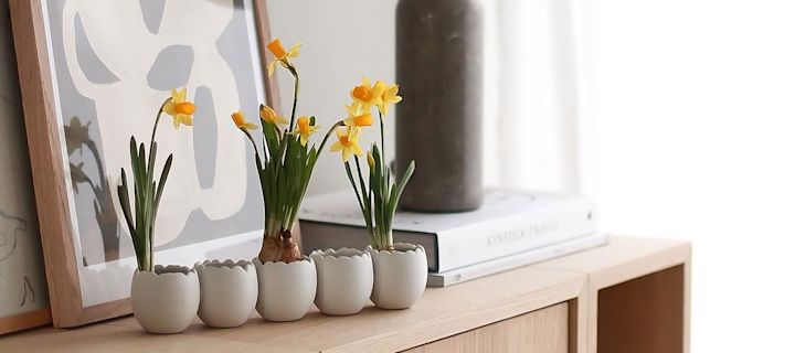 Kaksi eri muotoista ja kokoista Cooee Designin pallomaljakkoa, joissa on kevätkukkia, seisoo tarjottimella DBKD:n useiden pääsiäispupujen kolmosten vieressä @sachi_roooomin kotona.