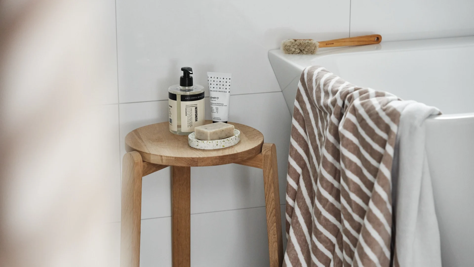 Ystävänpäivälahja: järjestä spa-päivä ja lahjoita tarvittavat tarvikkeet. Tässä NJRD:n Stripes-kylpypyyhe roikkuu kylpyammeen yläpuolella, ja sen vieressä on jakkara, jolla on Humdakin-saippua ja saippualusta.