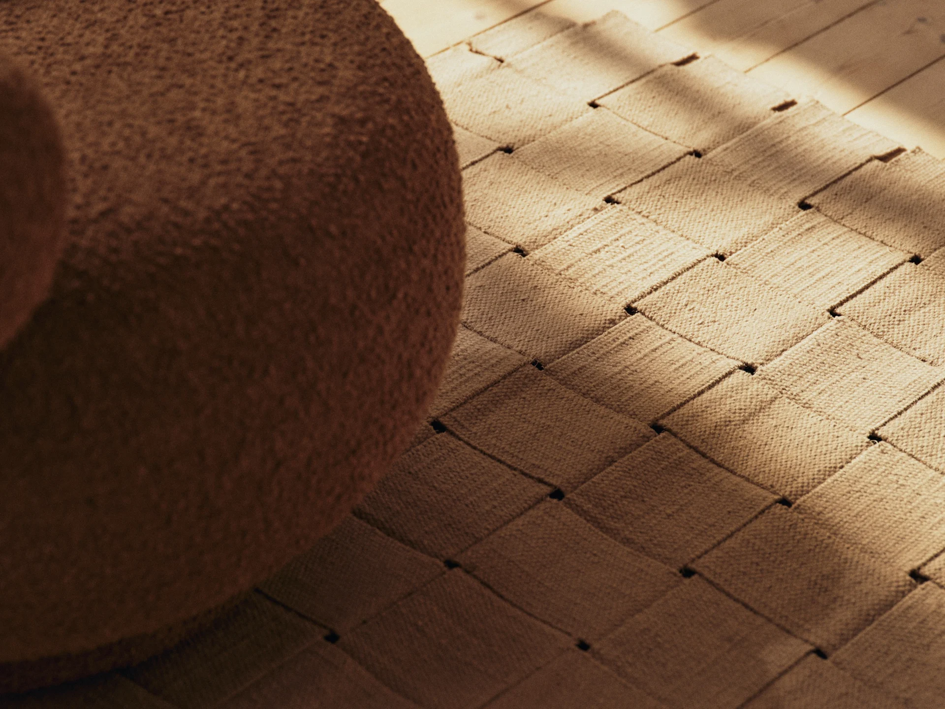 Ruskeat bukleekalusteet, kudottu matto ja puulattia auringonvalon ja varjojen kera.