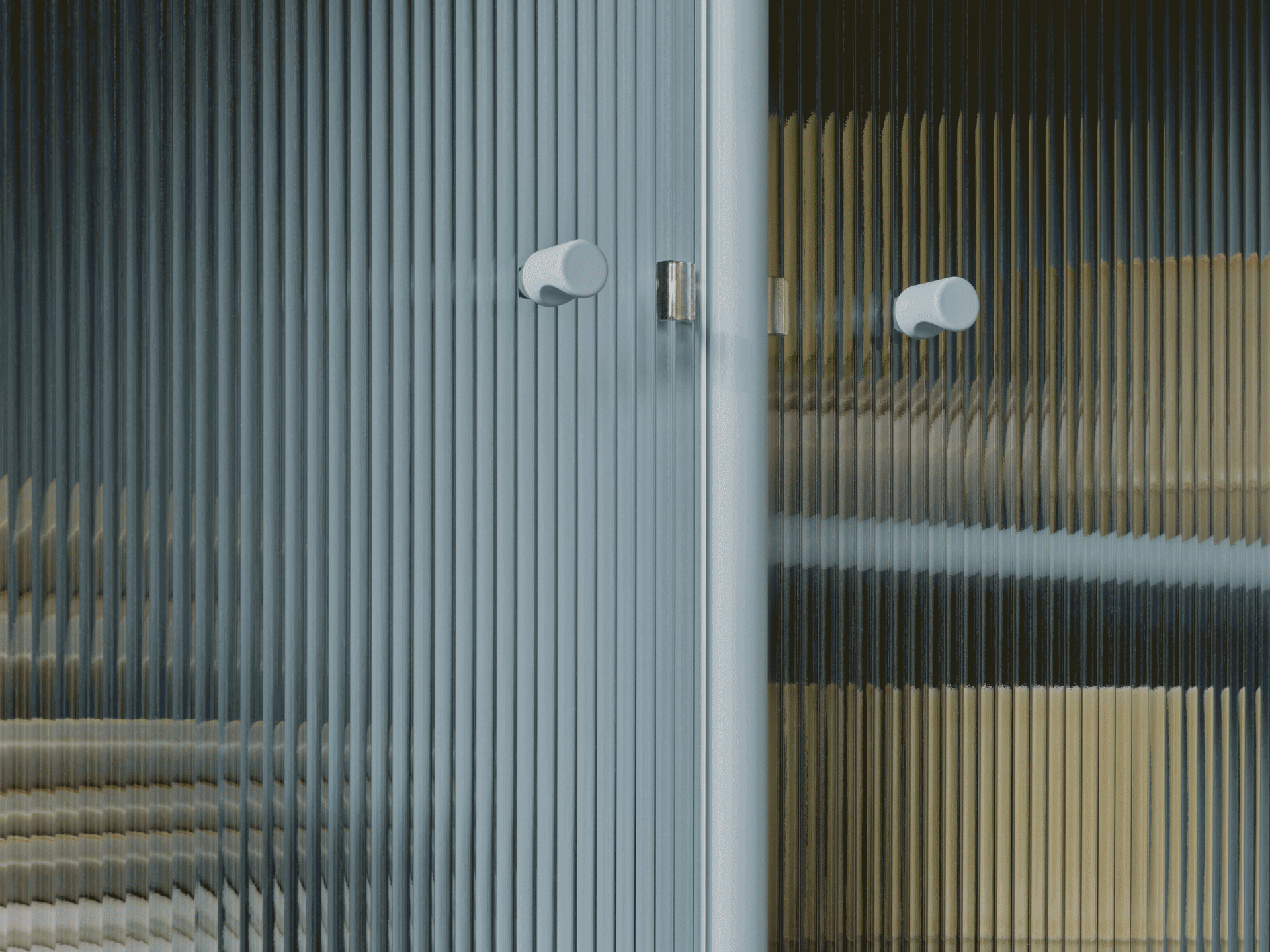 Lähikuva uurretusta lasiovesta, kaksi vaaleaa pyöreää kahvaa. Vääristyneitä värejä näkyy läpikuultavan pinnan läpi.