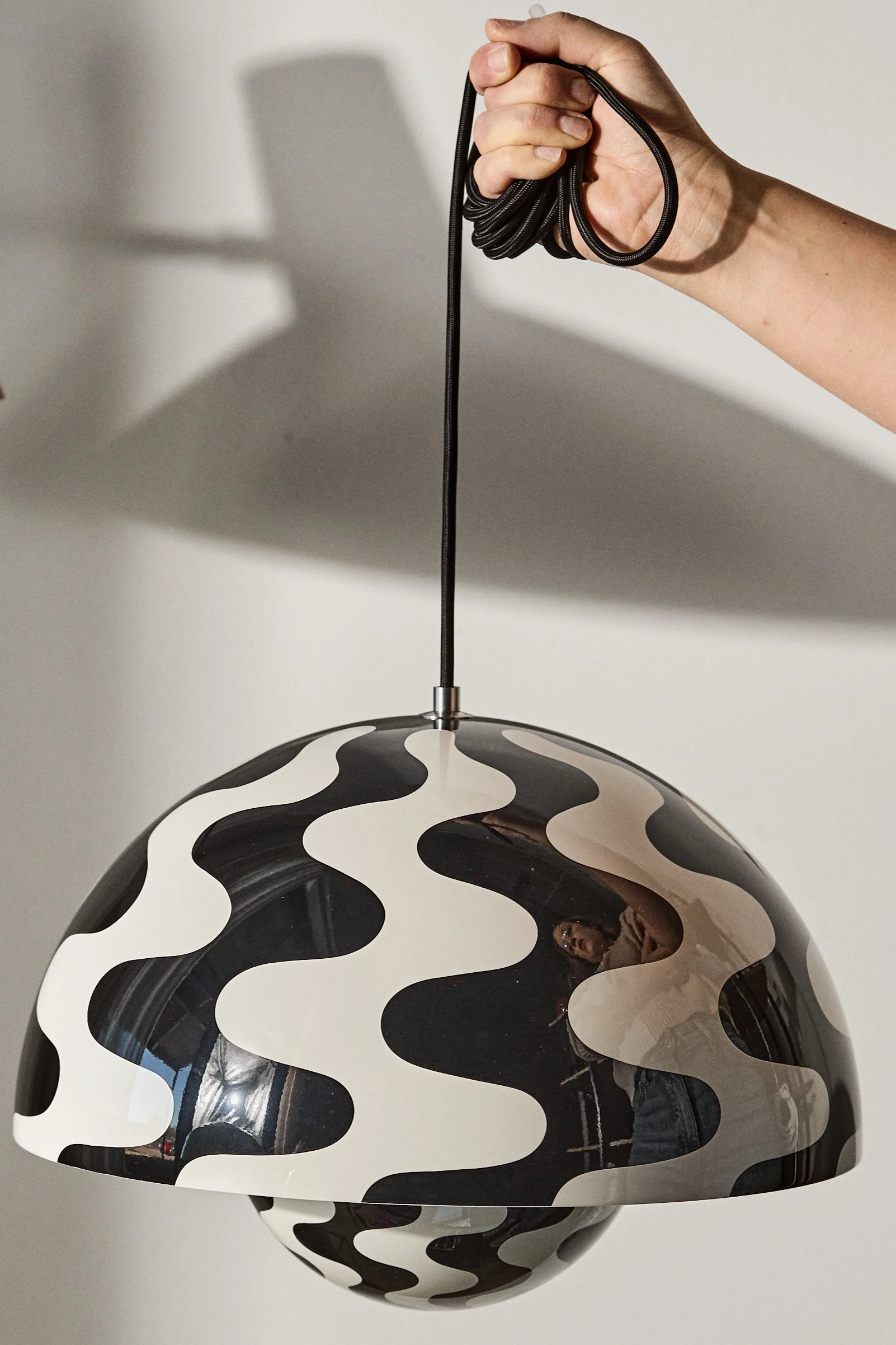 Kuvioidut kattovalaisimet olohuoneisiin voivat olla hauska tapa koristella ja valaista huonetta. Tässä näet käden pitelemässä Flowerpot VP7 -kattovalaisinta, jossa on mustavalkoinen kuvio.