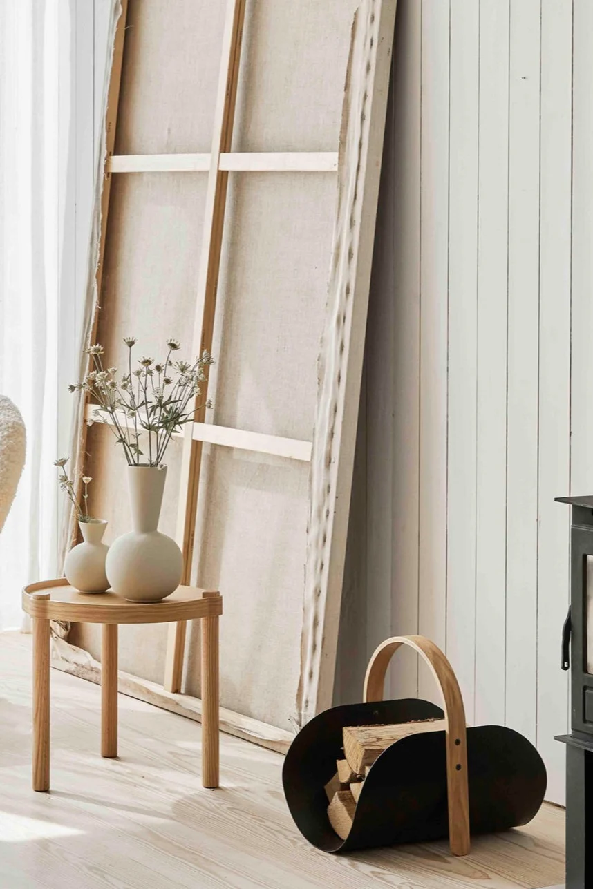 Kaksi Cooee-trumpettimaljakkoa värissä shell seisoo Woody-sivupöydällä Woody-puukorin vieressä. 