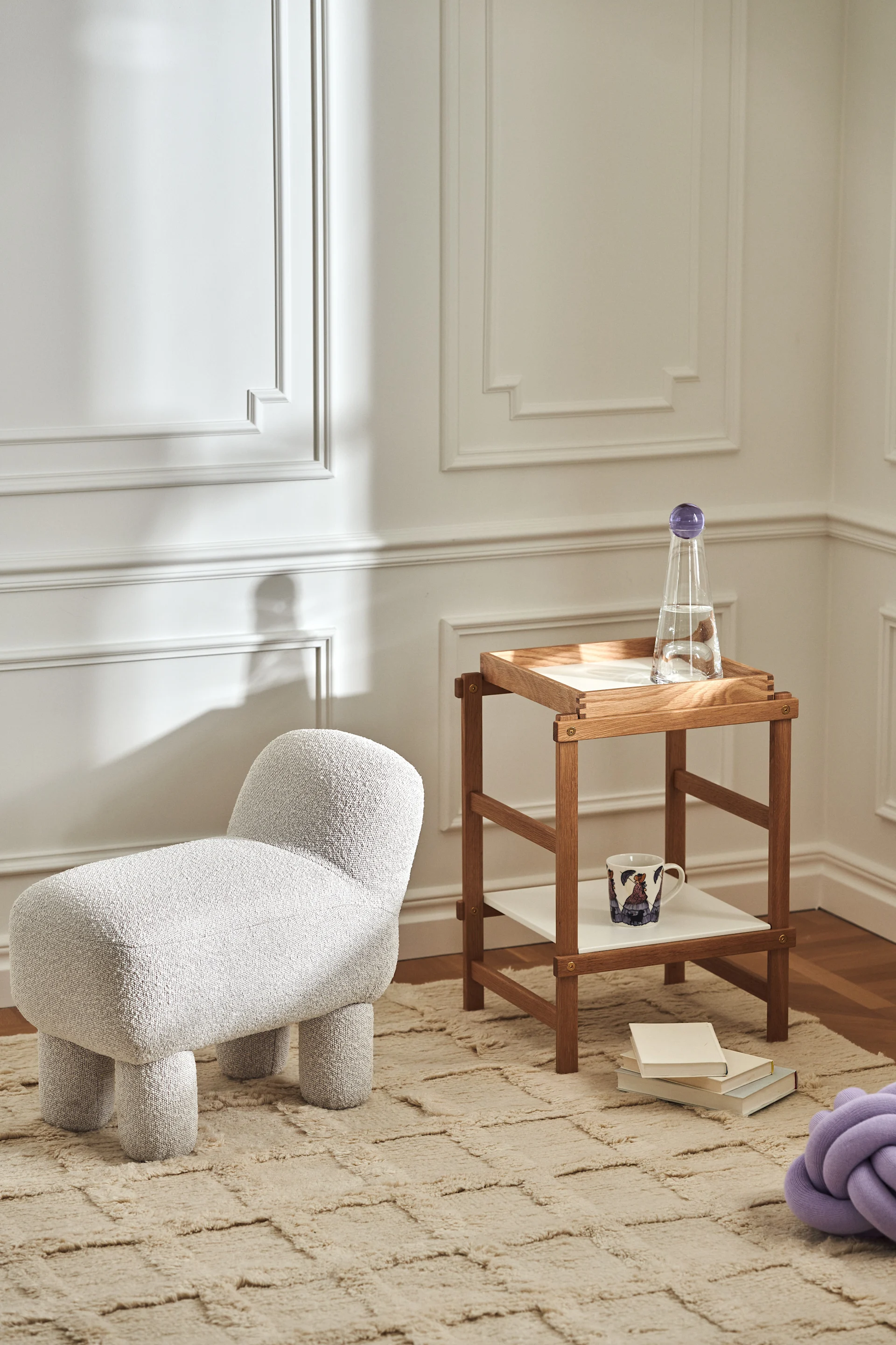 Tyylikäs olohuone, jossa on tuotteita merkiltä Design House Stockholm: Lulu rahi, Frame-hylly tammesta, Knot-tyyny laventelia ja Elsa Beskow -muki.